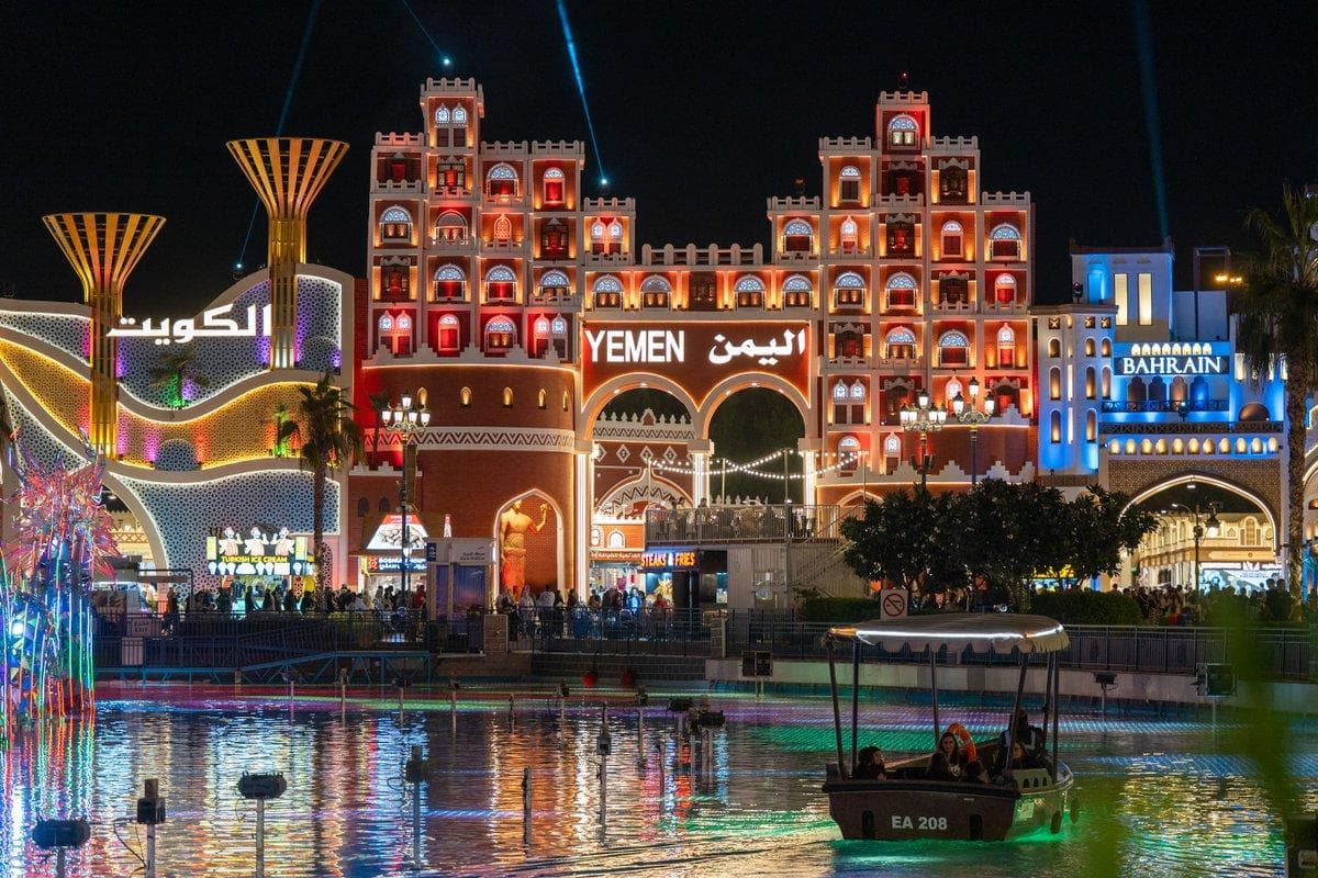 Global Village Dubai illuminated at night, featuring international pavilions, colourful architecture and a lively waterfront atmosphere.