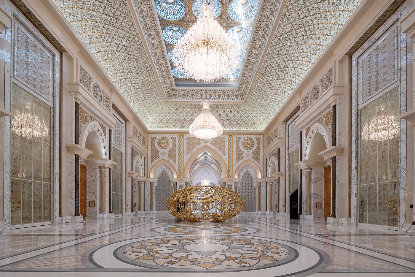 A view of "The Power of Words" golden sculpture by Mattar Bin Lahej in the palace hallway, a large hollow globe featuring interlaced Arabic calligraphy.