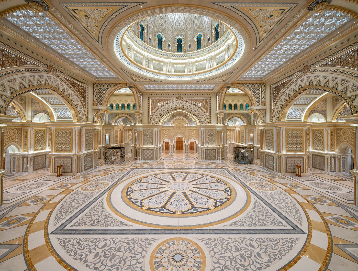 The interior of the Great Hall at Qasr Al Watan, featuring a magnificent golden dome with intricate geometric patterns, mirrored floors, and grand archways.