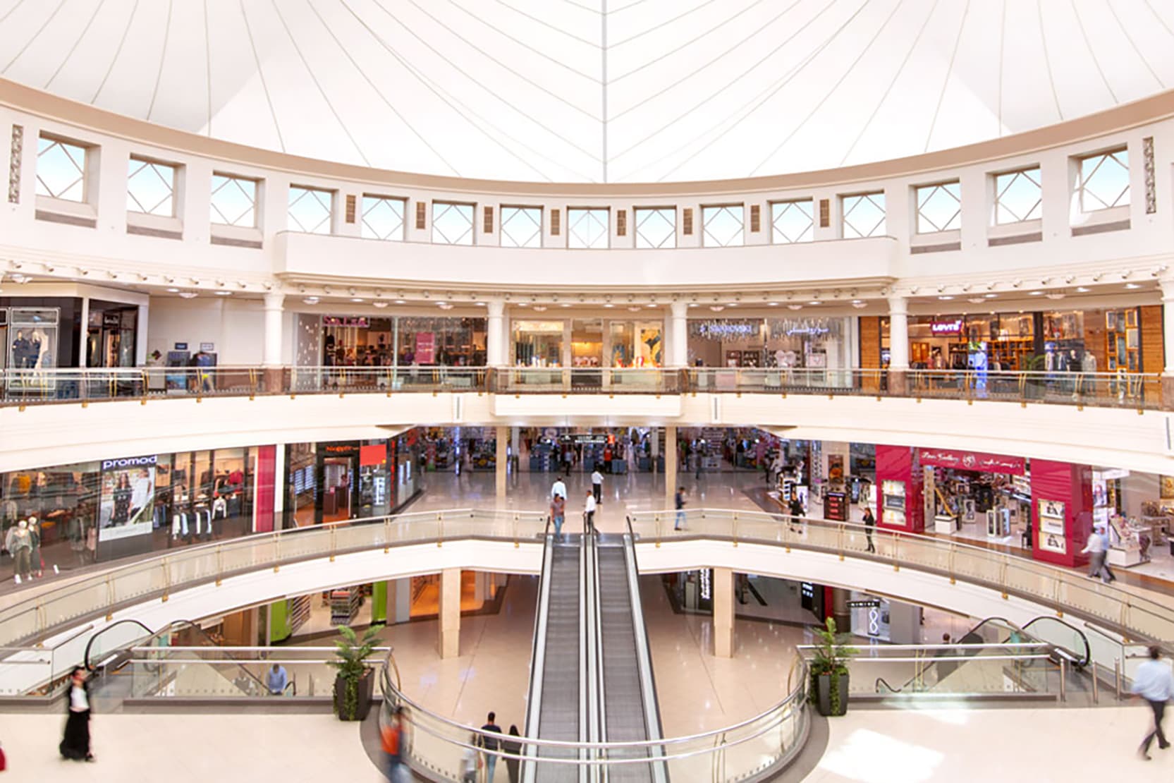 high-angle view of the bustling interior of City Centre Deira, showing the multi-level shopping aisles, central seating area, and the large glass skylight dome.