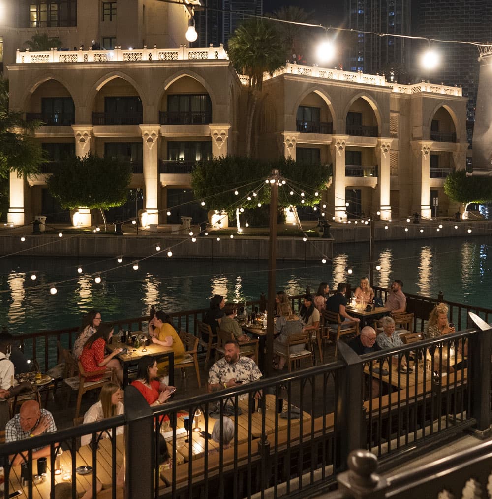 Waterfront outdoor terrace night dining at The Meat Co Souk Al Bahar with Dubai skyline view