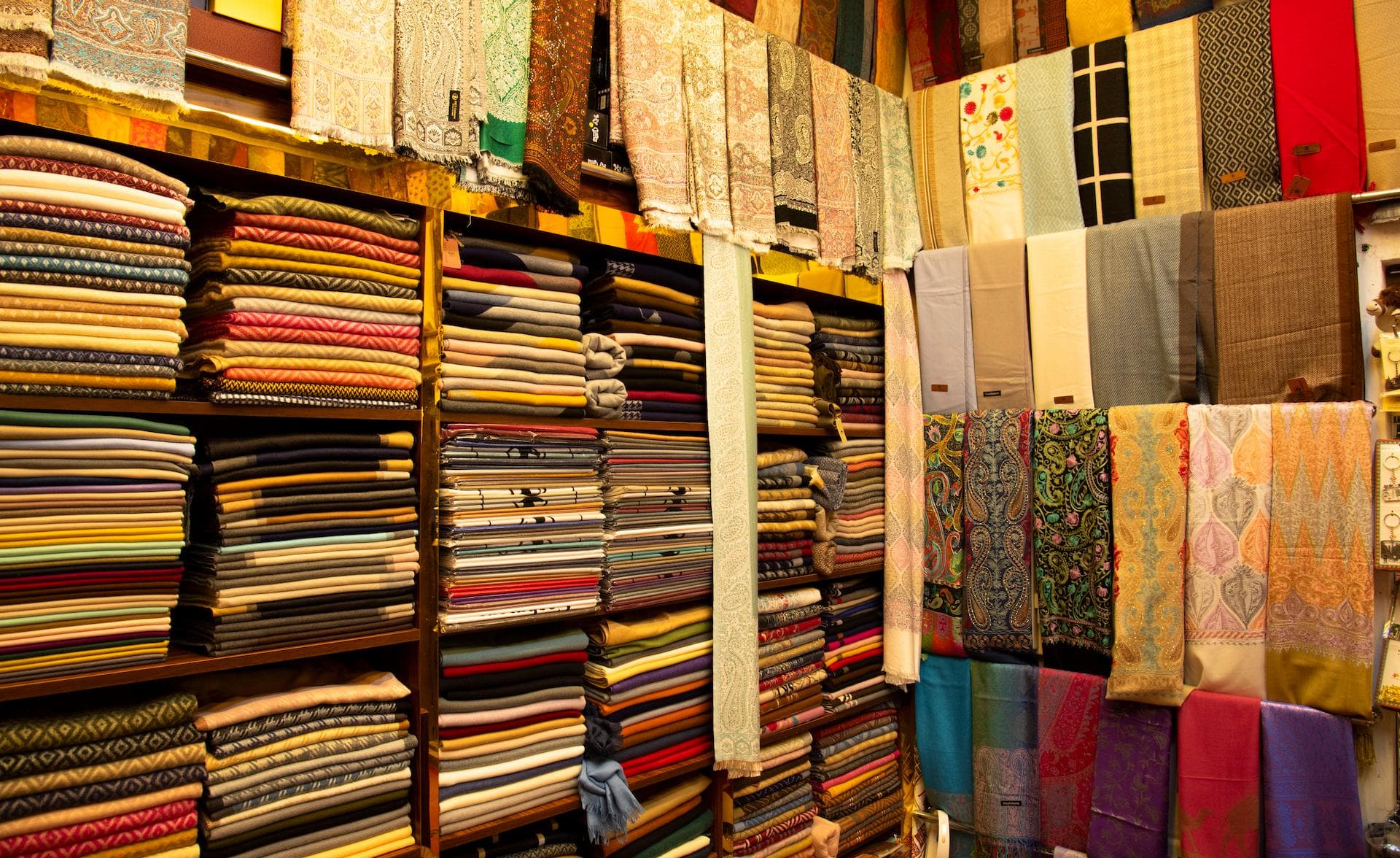 Colourful traditional fabrics, scarves and textiles stacked on shelves inside a shop at Al Fahidi Historical Neighbourhood Dubai