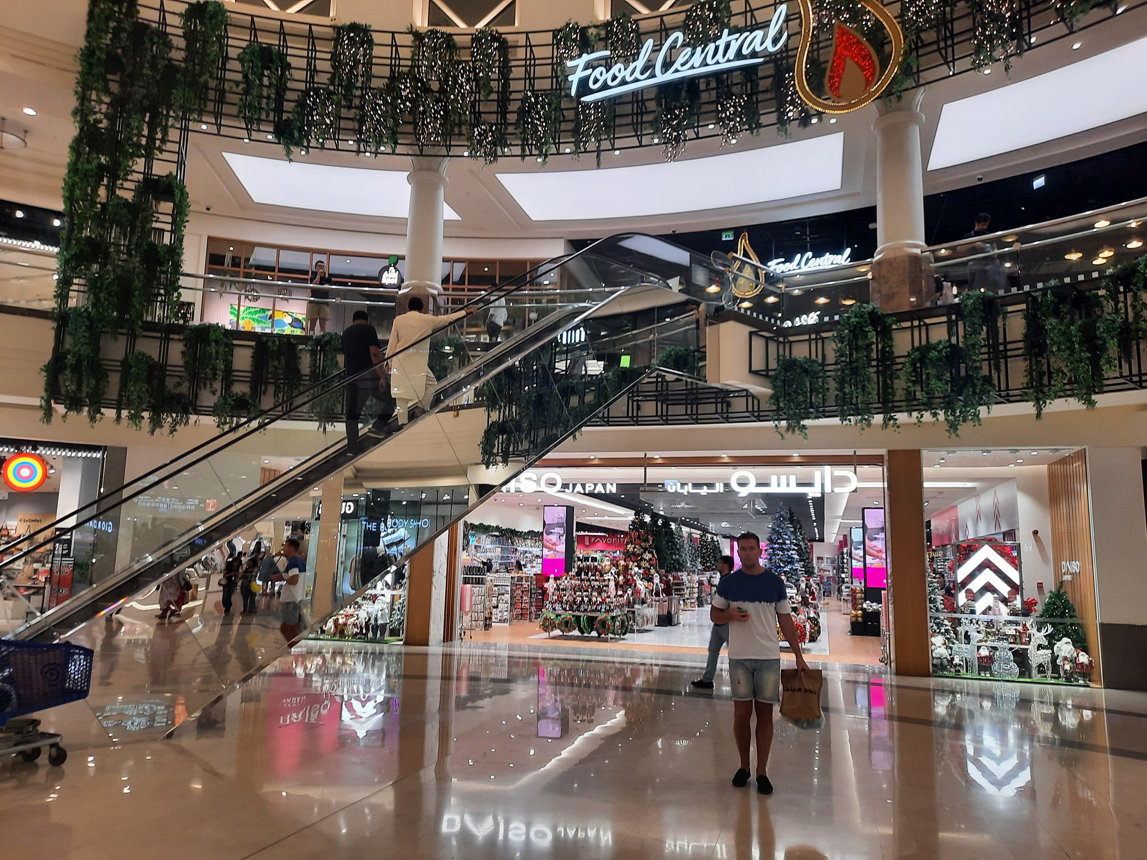 origA street-level view of the City Centre Deira landmark signage near a parking area, with the mall's unique architectural wings visible in the background.